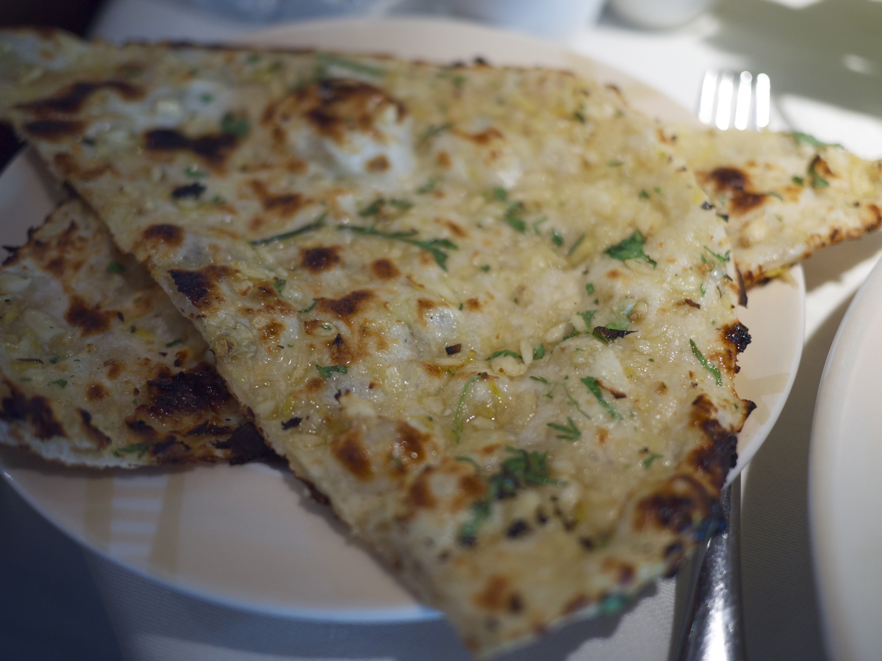 Fresh baked naan bread stacked on a plate
