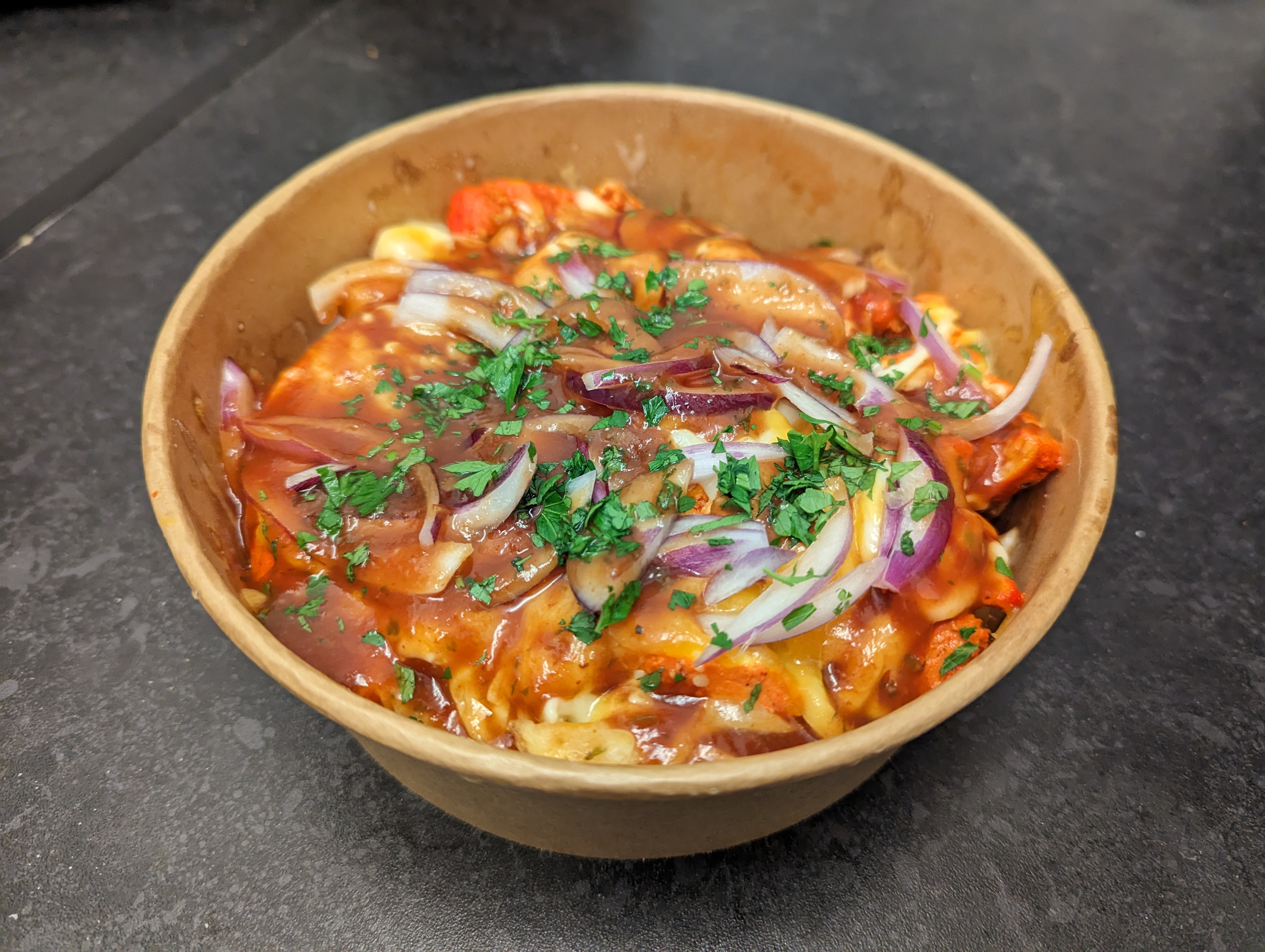 Close-up of loaded fries piled high with toppings, steam rising