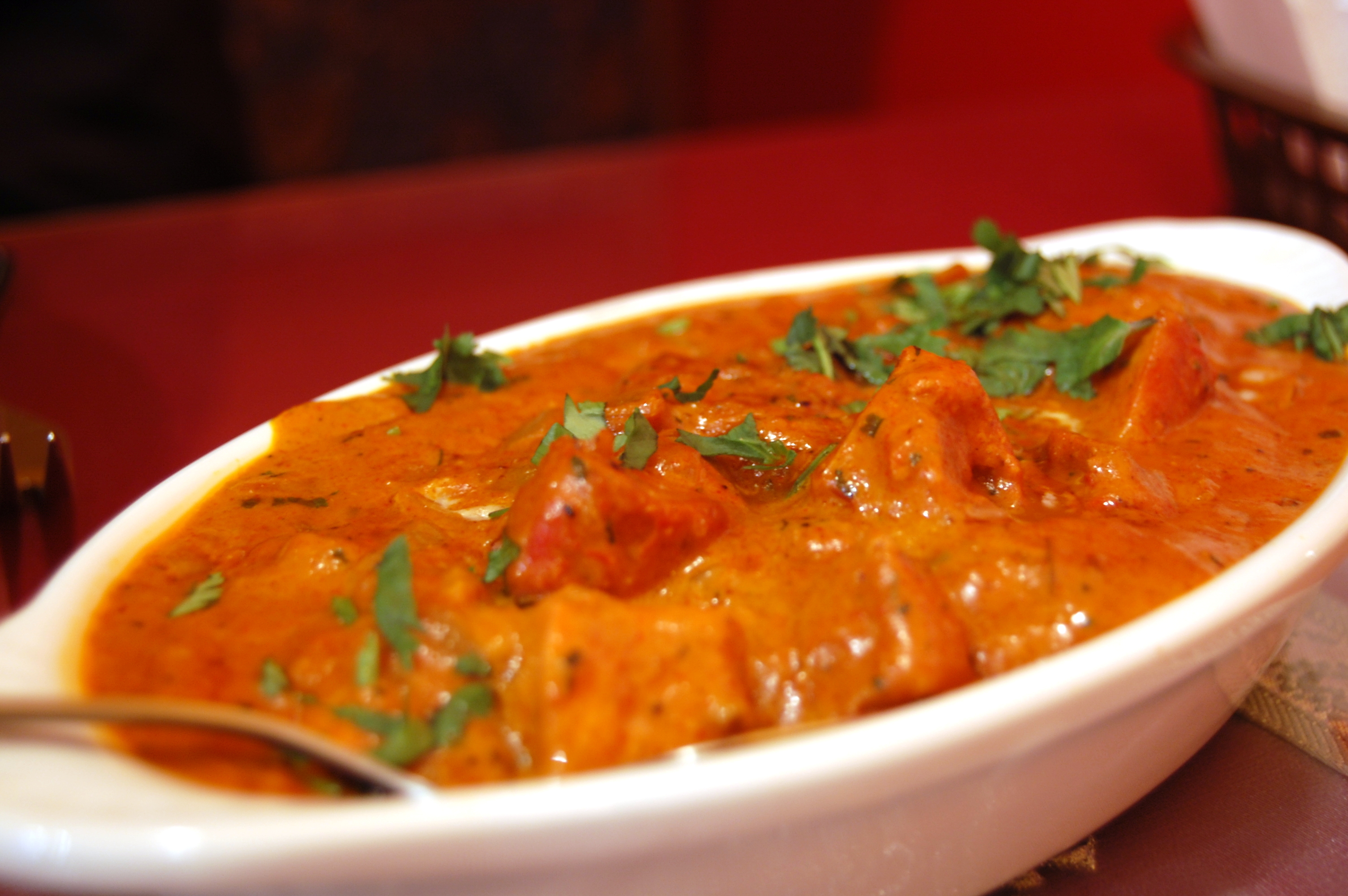 Bowl of butter chicken curry with rice and naan